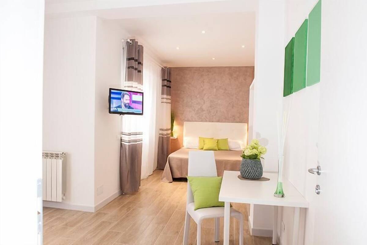 Quarto de hotel moderno com cama, televisão, escrivaninha e cadeira.