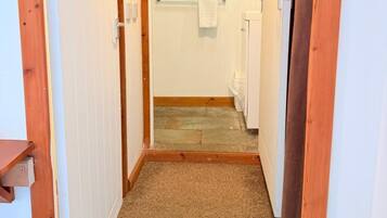 A narrow hallway leading to a bathroom with a towel rack and a radiator.