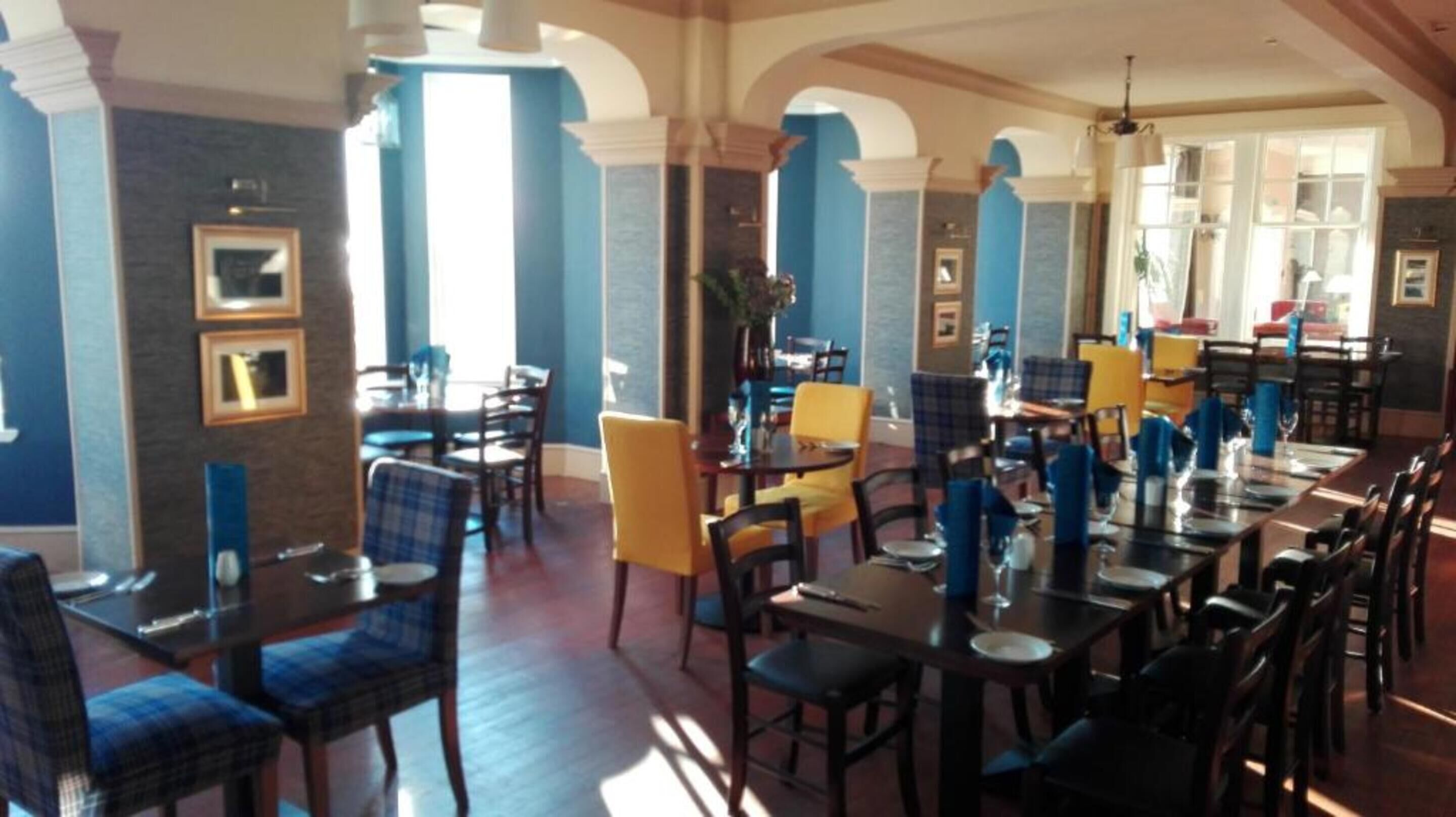A restaurant with a long dining area, multiple tables, and chairs.