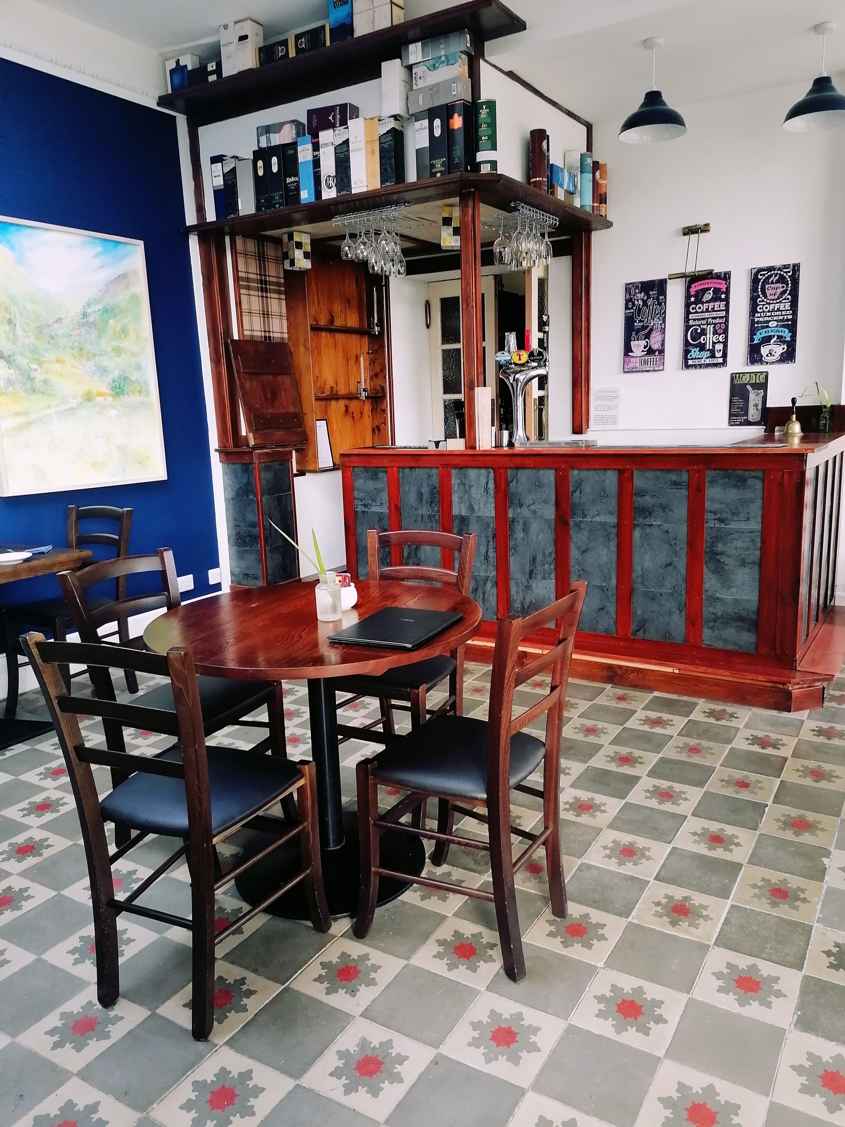 Ein Café-Interieur mit Holztisch und -stühlen, einer Theke und Regalen voller Kaffee.