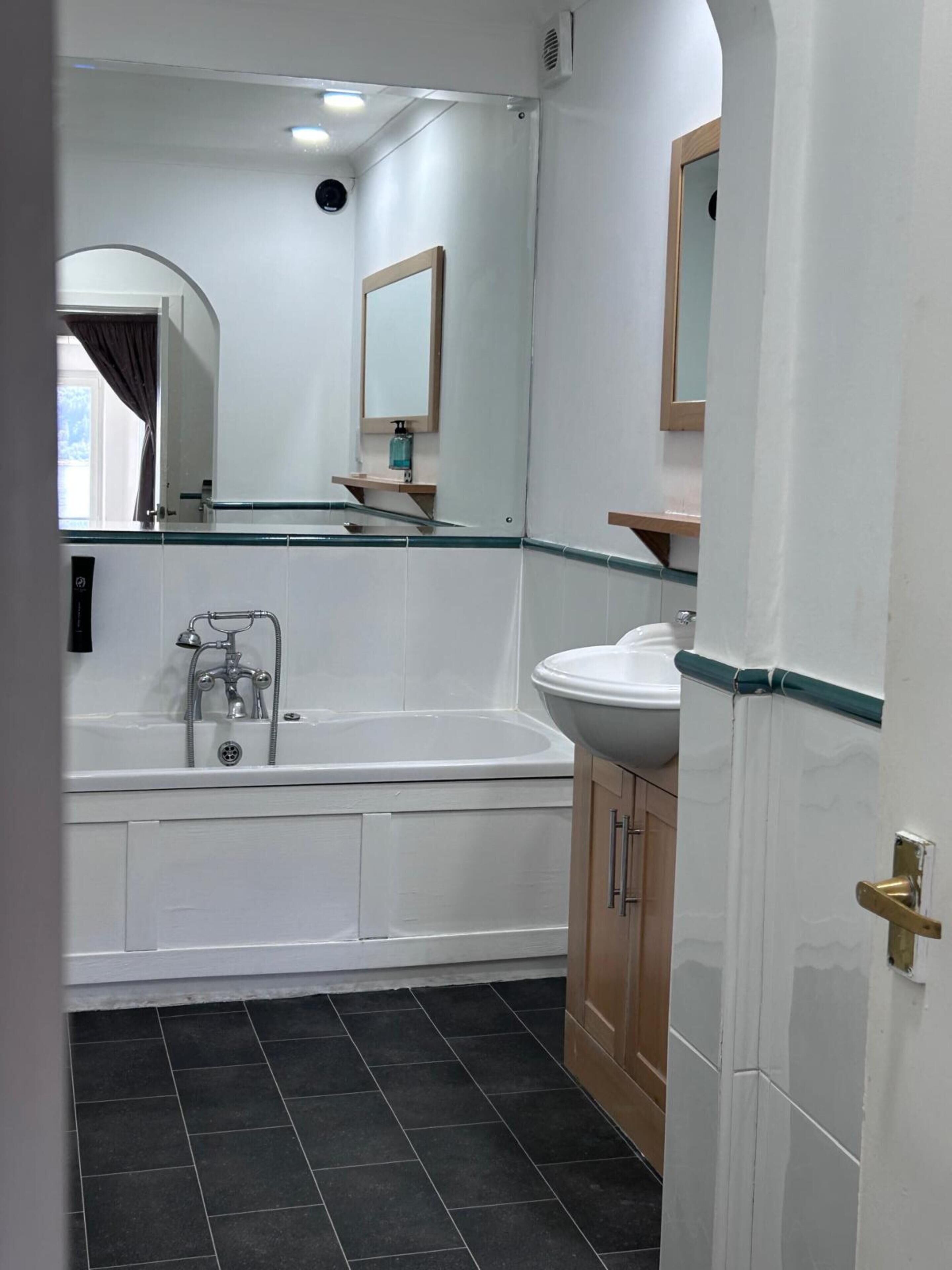 A bathroom with a bathtub, a sink, and a mirror.