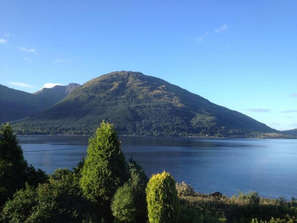 A mountain with a lake in the foreground and a forested area in the midground.