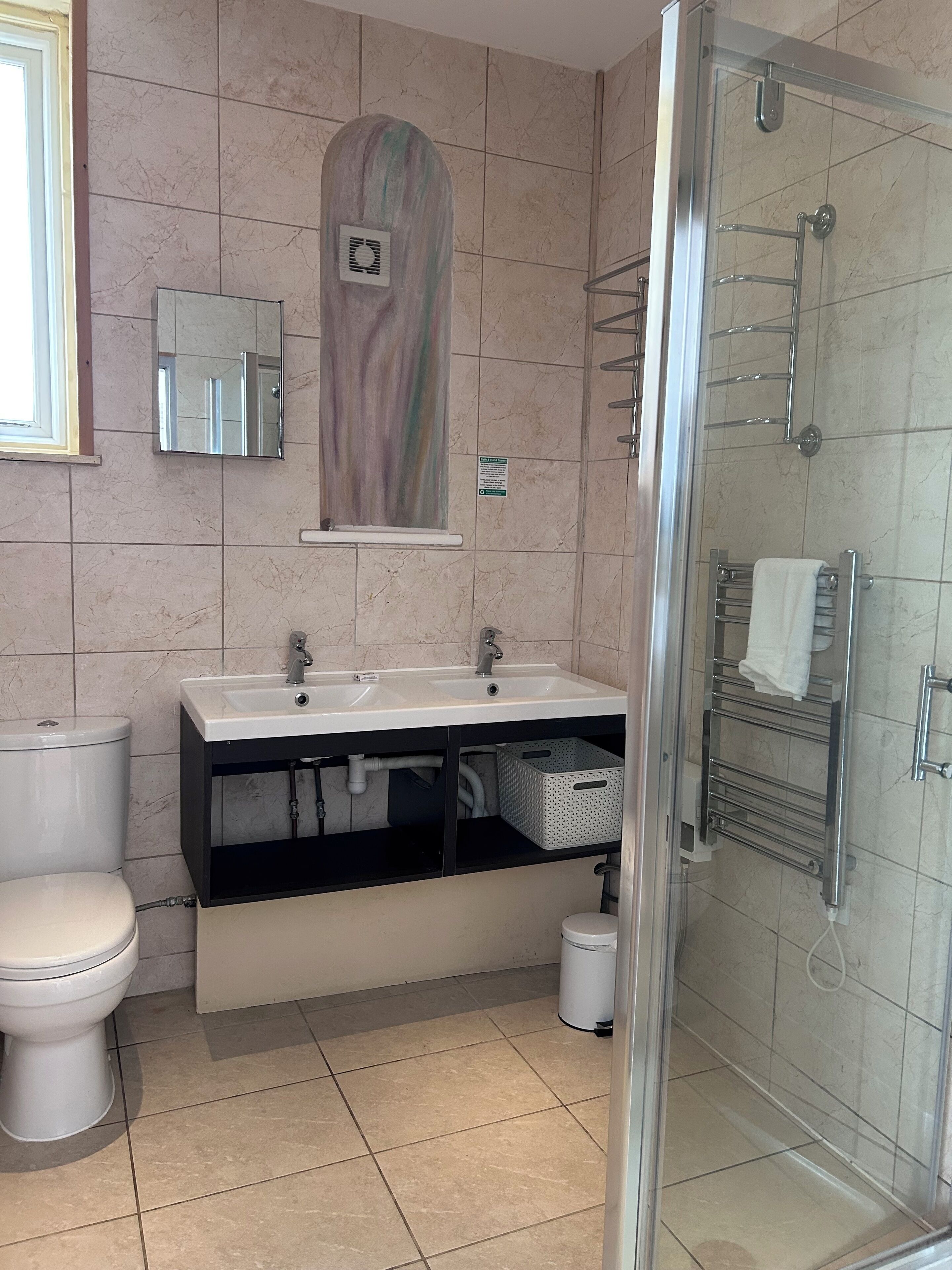 A modern bathroom with a glass shower enclosure, a white sink with a mirror above, and a toilet.
