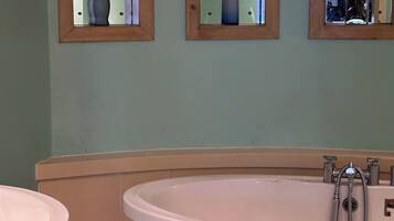 A bathroom with a freestanding bathtub, a sink, and three mirrors with vases.