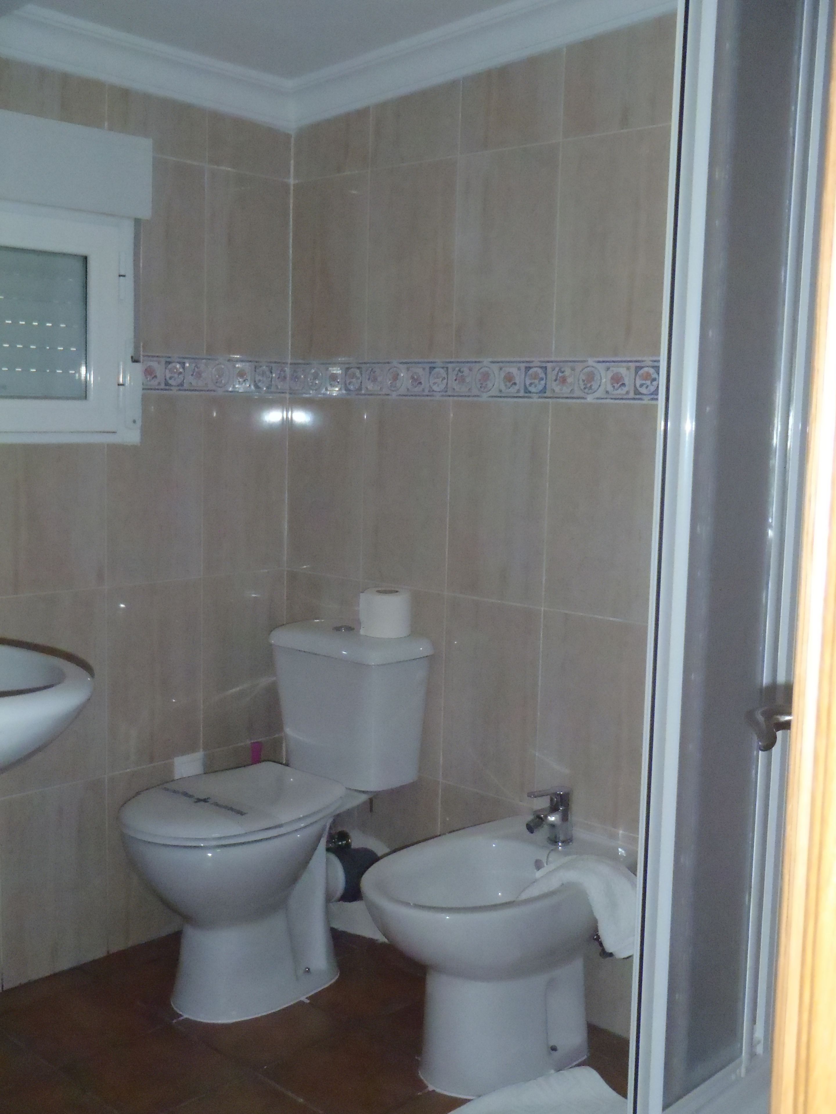 Un baño con dos inodoros, un lavabo y una zona de ducha.