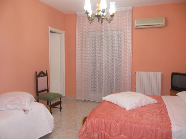 Un dormitorio con dos camas, una silla, un radiador y un televisor.