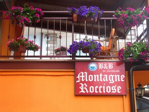 Placa para 'Montagne Roccose' com cestos suspensos de flores.