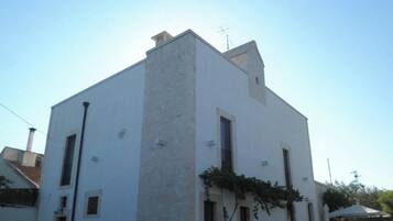 A white building with a flat roof, multiple windows, and a chimney.