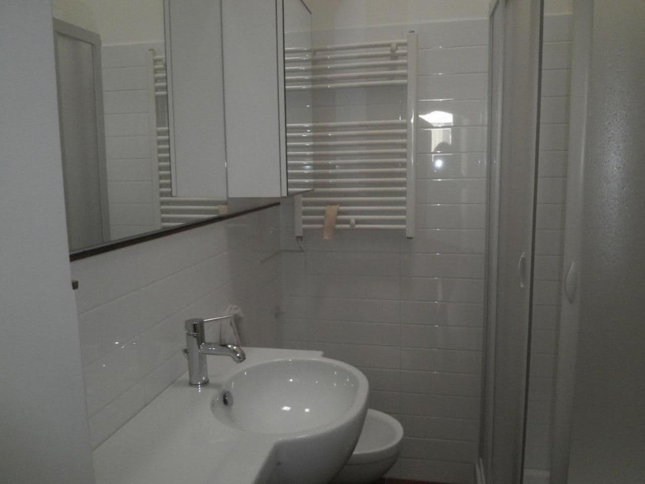 A bathroom with a white sink, a mirror, and a shower enclosure.