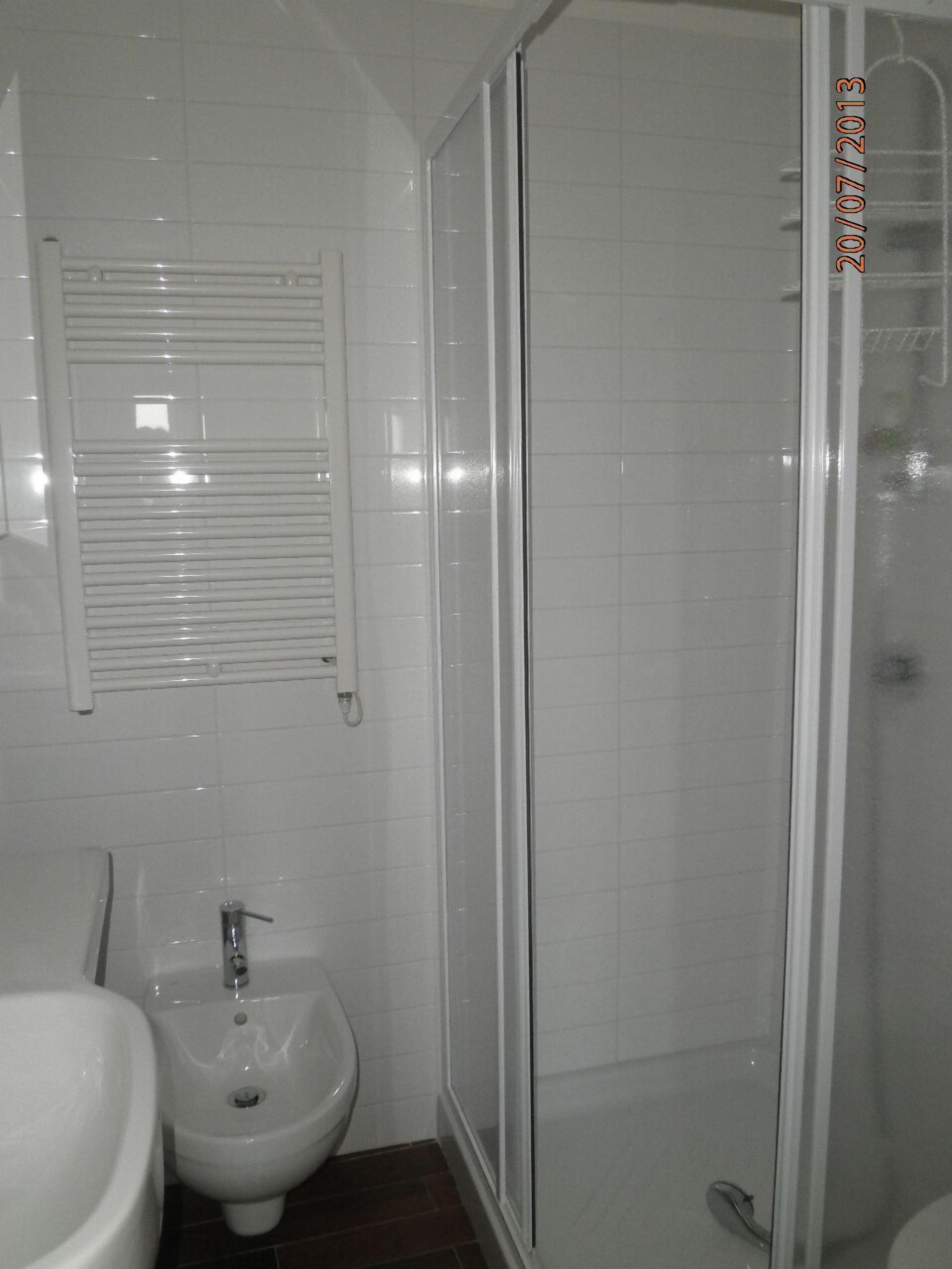 Un baño con bidé, inodoro y cabina de ducha con mampara de vidrio.