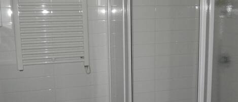 Un baño con bidé, inodoro y cabina de ducha con mampara de vidrio.