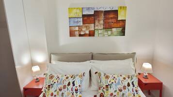 Camera d'hotel con un letto, due comodini, due lampade e un quadro astratto dai colori vivaci appeso alla parete.