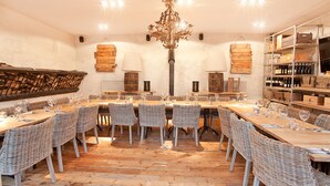 A dining area with a long wooden table, wicker chairs, and a chandelier. - The Castle Inn (Harrogate)