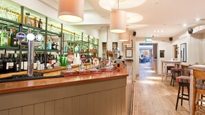 A bar area with a wooden counter, multiple beer taps, and a variety of bottles on shelves. - The Castle Inn (Harrogate)