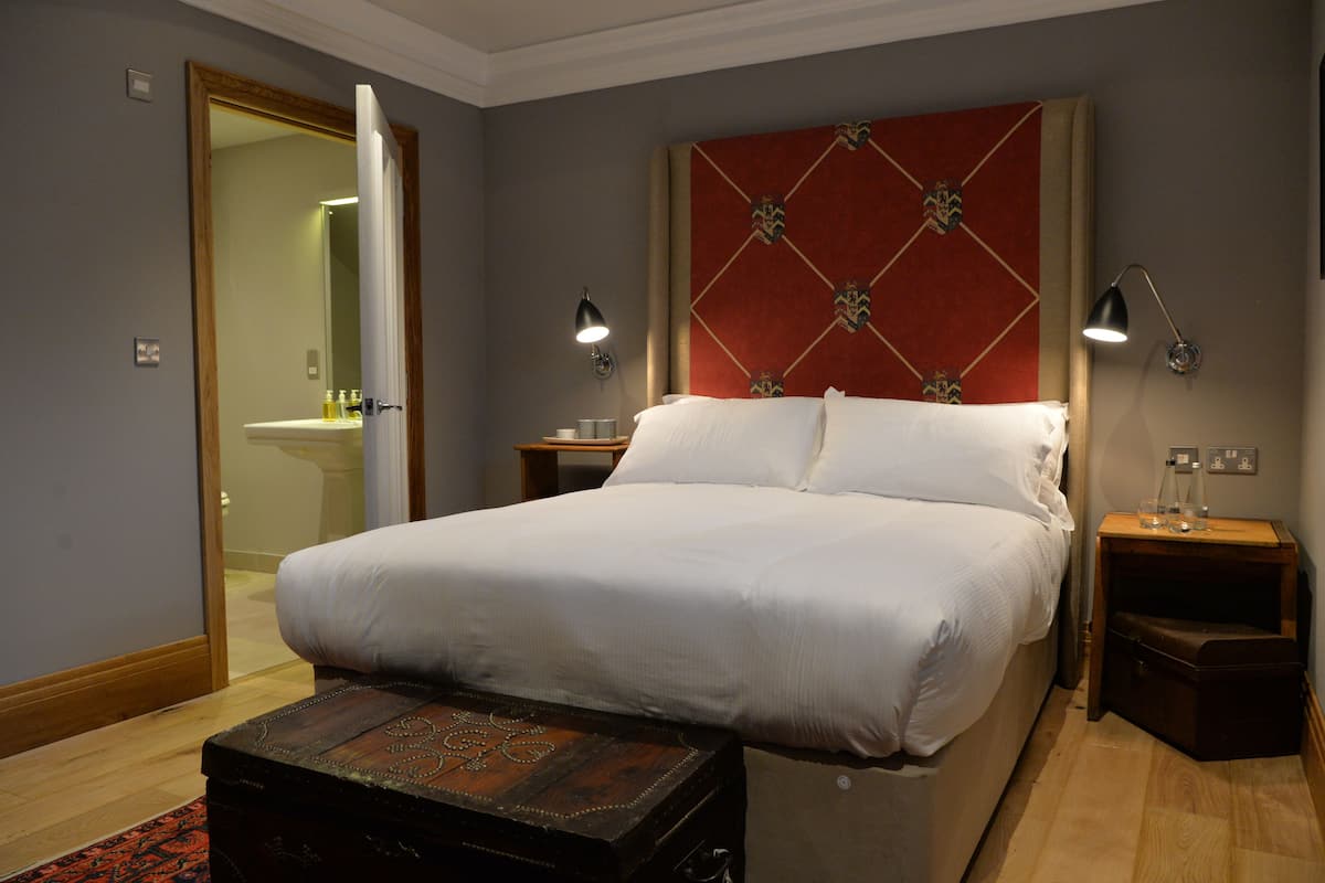 A neatly arranged hotel room with a large bed, bedside tables, a wooden chest, and a mirror.