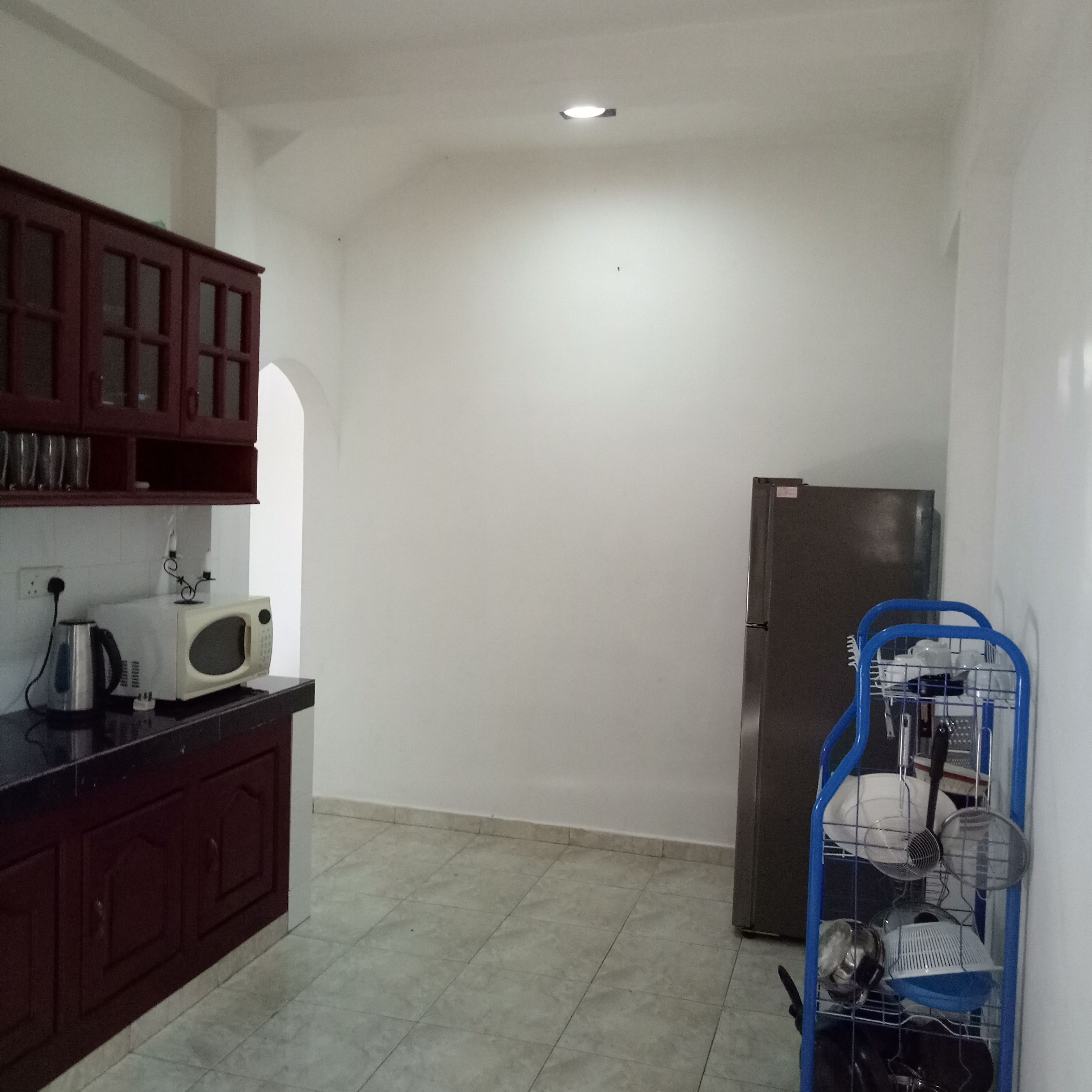 A compact kitchen with a microwave, kettle, and a refrigerator.