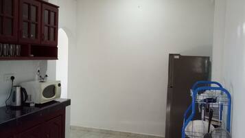 A compact kitchen with a microwave, kettle, and a refrigerator.