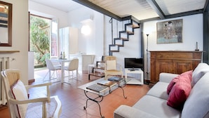 Un vaste espace de vie comprenant un escalier, un coin repas et un espace salon confortable avec un canapé et des fauteuils.