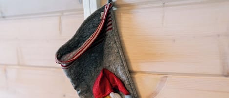 Un calcetín navideño gris con un lazo rojo y una barba blanca colgado en una pared de madera.