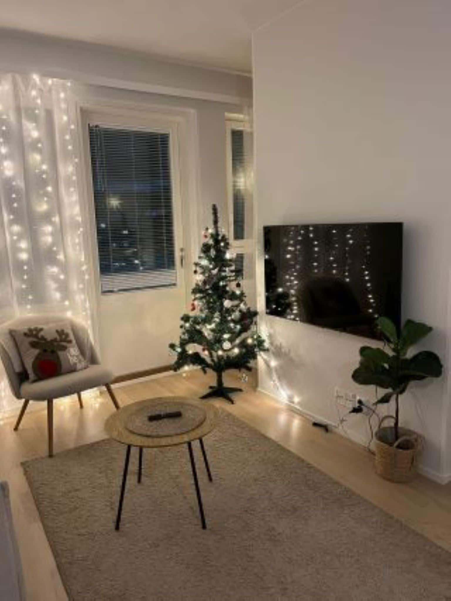 Una sala de estar con un árbol de Navidad, un televisor de pantalla plana, un sillón y una mesa de centro.