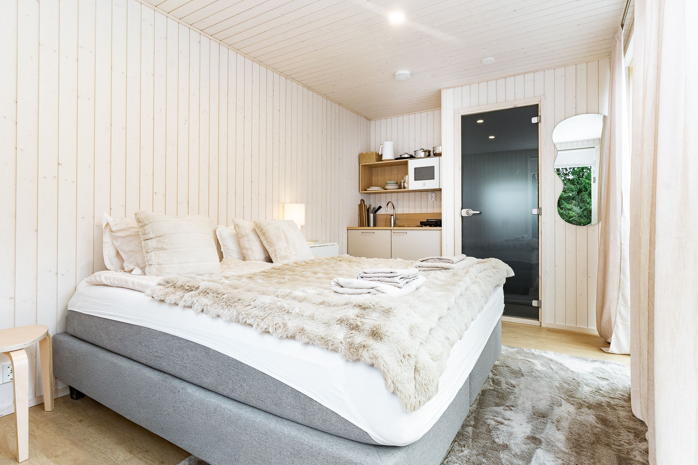A bedroom with a bed, bedside table, and a view of the bathroom.