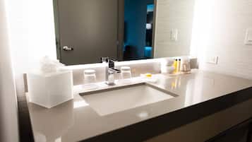 Un baño moderno con un espejo grande, un lavabo y artículos de aseo.