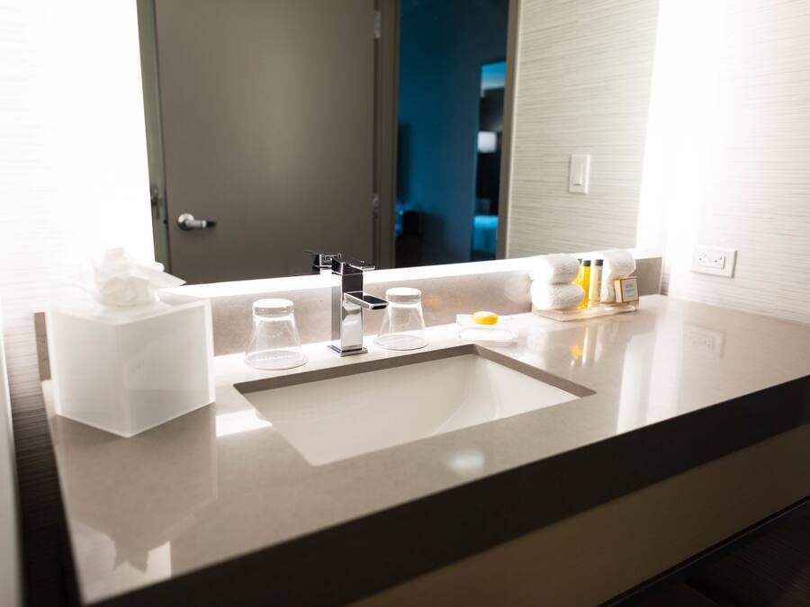 A modern bathroom with a large mirror, a sink, and toiletries.