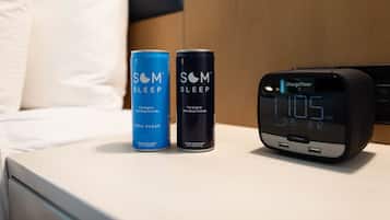 Una mesita de noche con dos latas de SOM Sleep Formula y un reloj digital ChargeTime que marca las 11:05 AM.