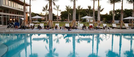 Una piscina al aire libre, sillones reclinables de piscina