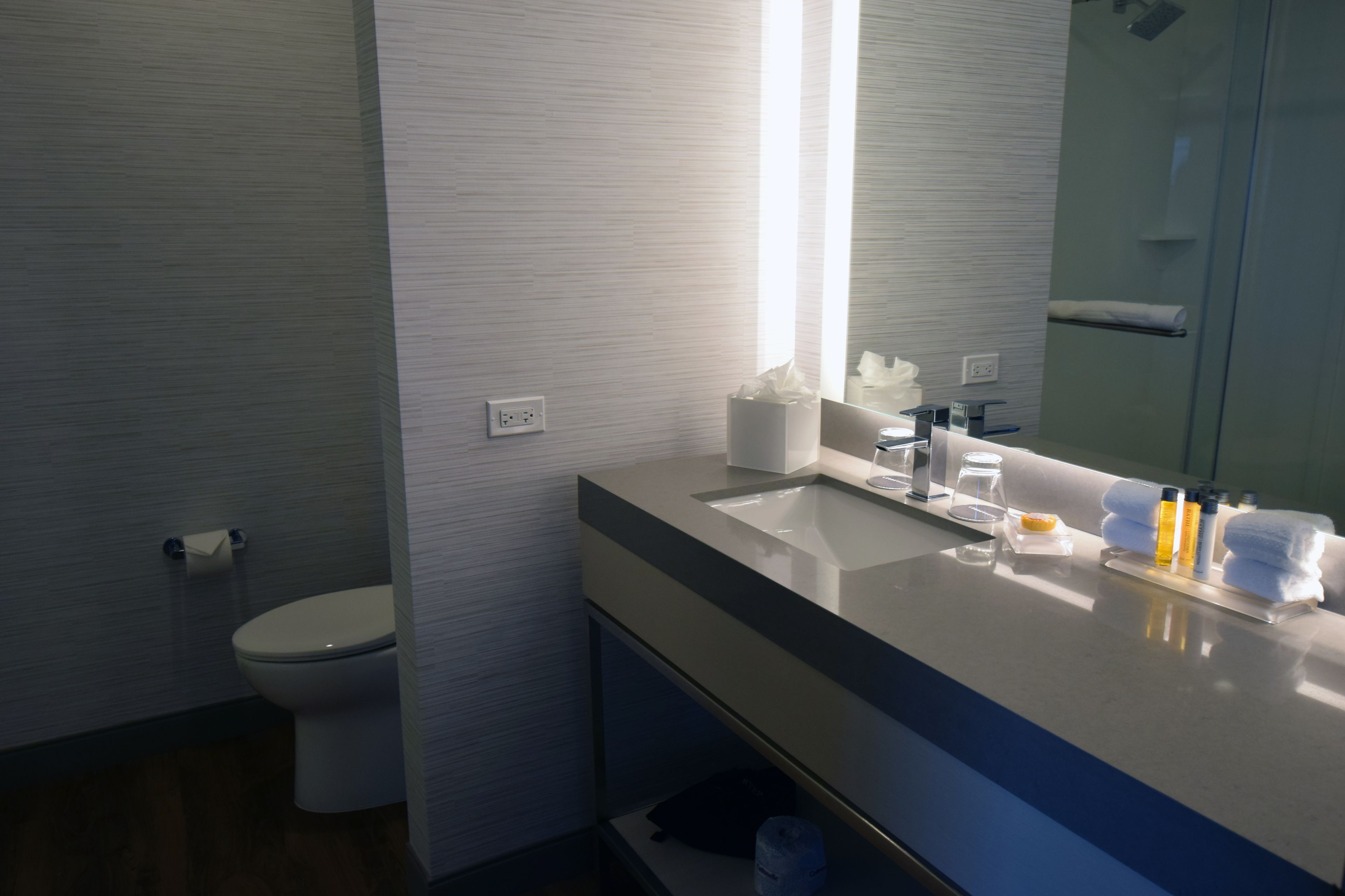 A modern bathroom with a white sink, mirror, and toilet.
