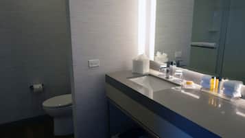 A modern bathroom with a white sink, mirror, and toilet.