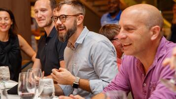 A group of people seated at a table with wine glasses, engaged in conversation.