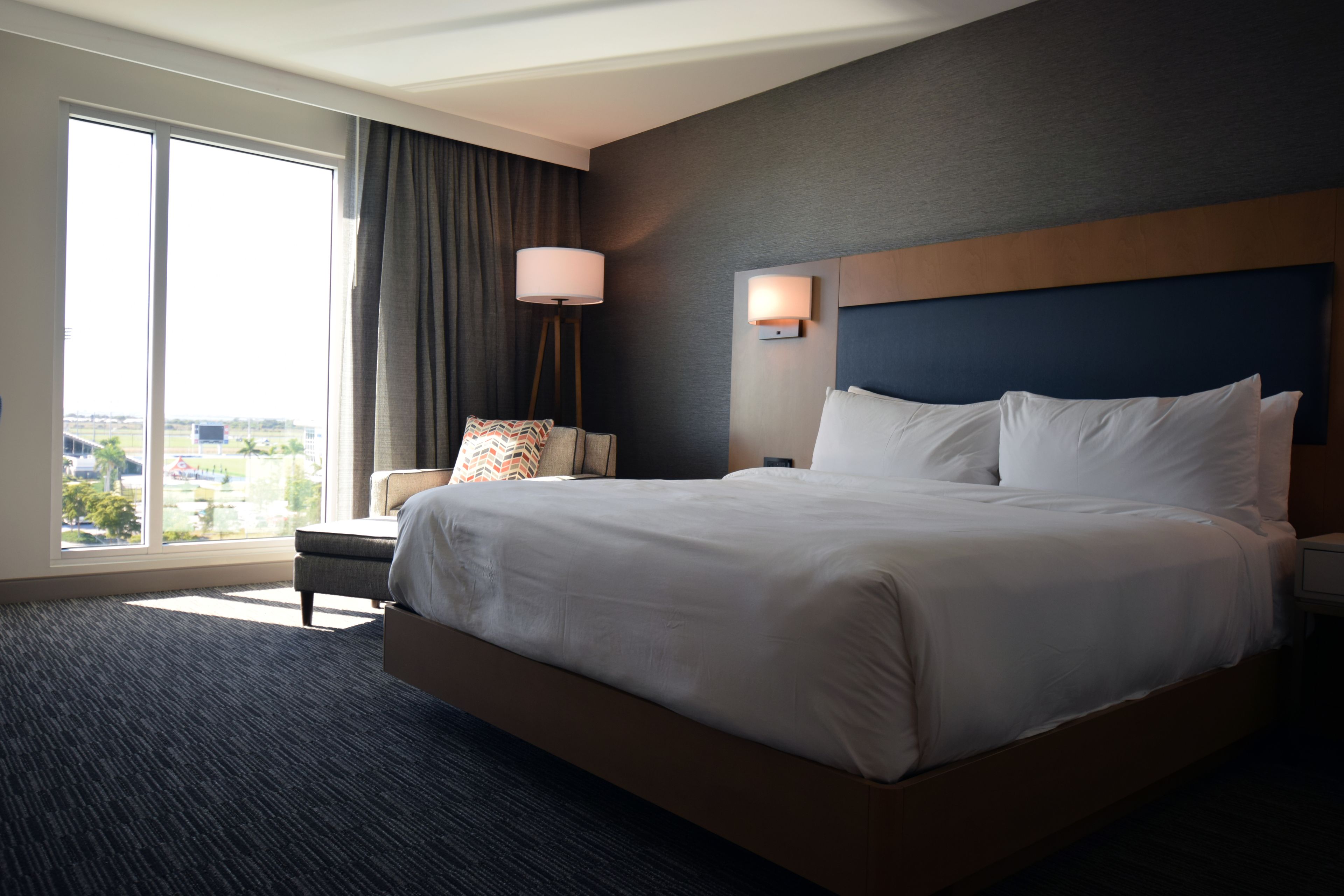 Une chambre d’hôtel avec un grand lit, une chaise, une lampe et une vue sur la ville.