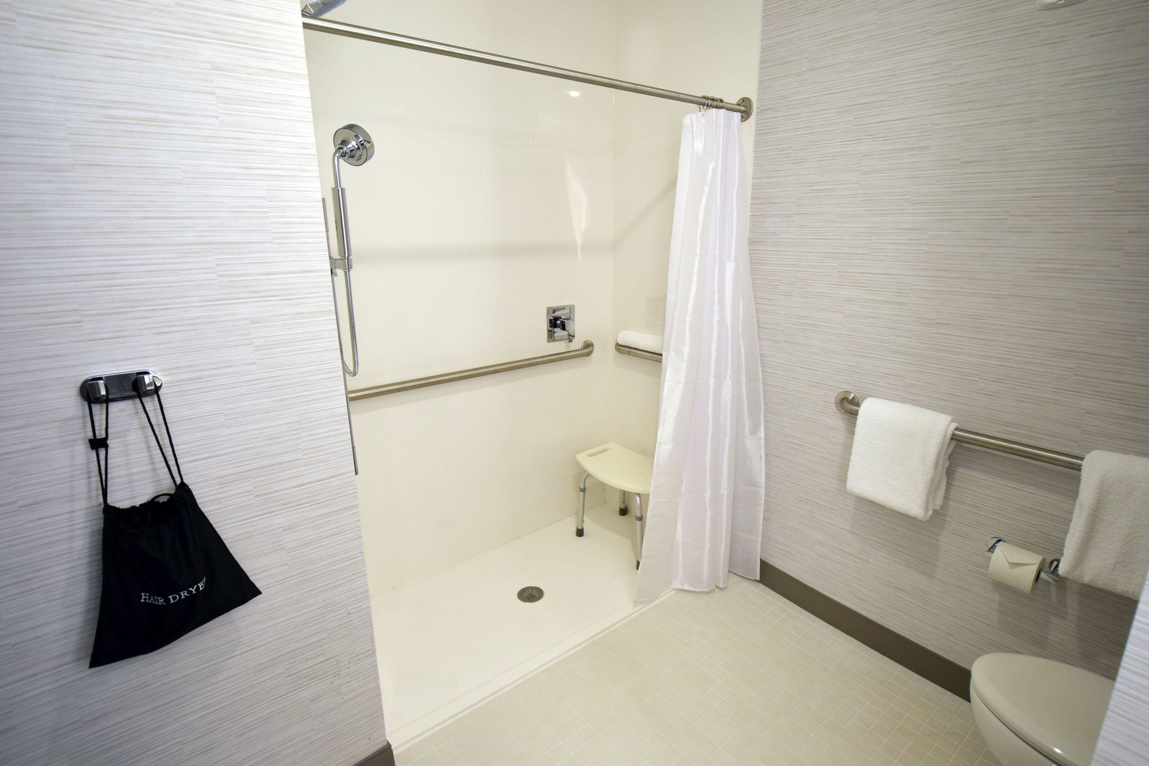 Un baño moderno con cabina de ducha, inodoro y lavamanos pequeño.