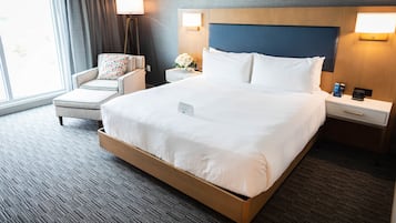 A hotel room with a large bed, a chair, a nightstand, and a lamp.