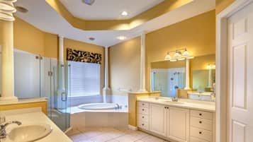 Une salle de bain moderne dotée d’une douche à parois de verre, d’une grande baignoire et d’un meuble-lavabo avec un évier et un miroir.