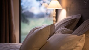 A bed with pillows and a lamp in a room with a view of greenery outside. - Chambres D'hôtes Mas D'eymard (Arles)