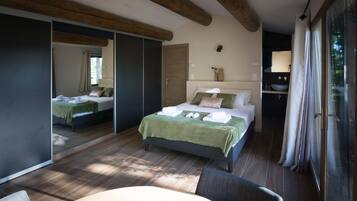 Een moderne slaapkamer met een groot bed, een apart zithoekje en een badkamer die zichtbaar is door een geopende deur.