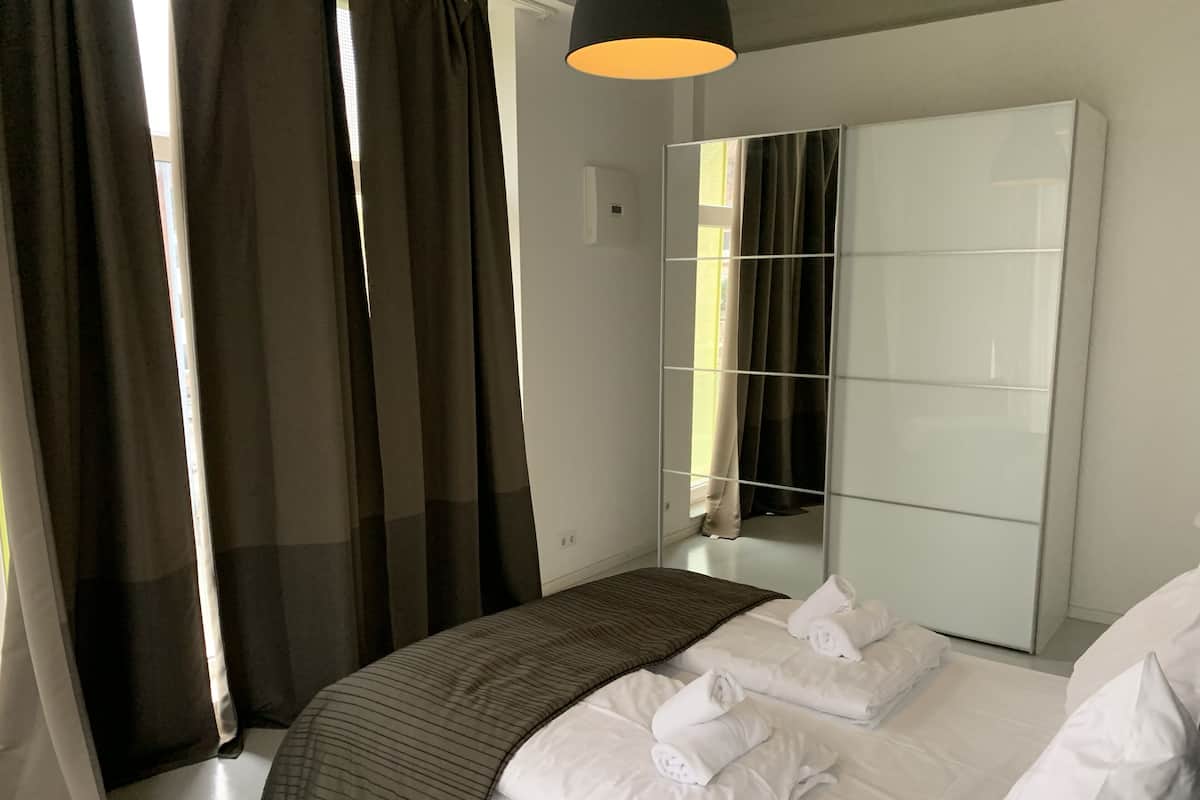 Quarto moderno com uma cama grande, um guarda-roupa e um espelho.