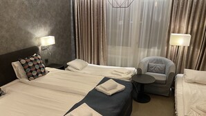 A hotel room with two beds, a chair, and a small table. - Hotell Rättvik (Rattvik)