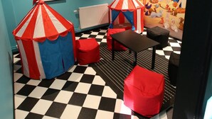 A children's play area with a checkered floor, red and blue play tents, and a mural of a fairy tale scene. - Hotell Rättvik (Rattvik)