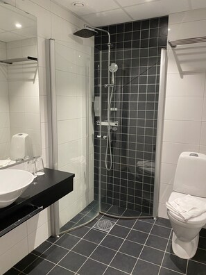 A modern bathroom with a glass-enclosed shower, a white toilet, and a black countertop with a sink.