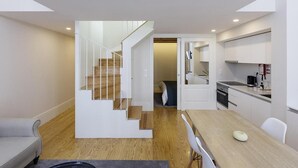 A modern apartment with a staircase leading to a loft bedroom, a dining area, and a kitchen. - Mercado dos Poetas (Porto)