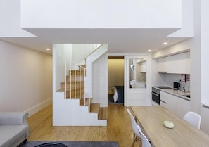 A modern apartment with a staircase leading to a loft bedroom, a dining area, and a kitchen. - Mercado dos Poetas (Porto)