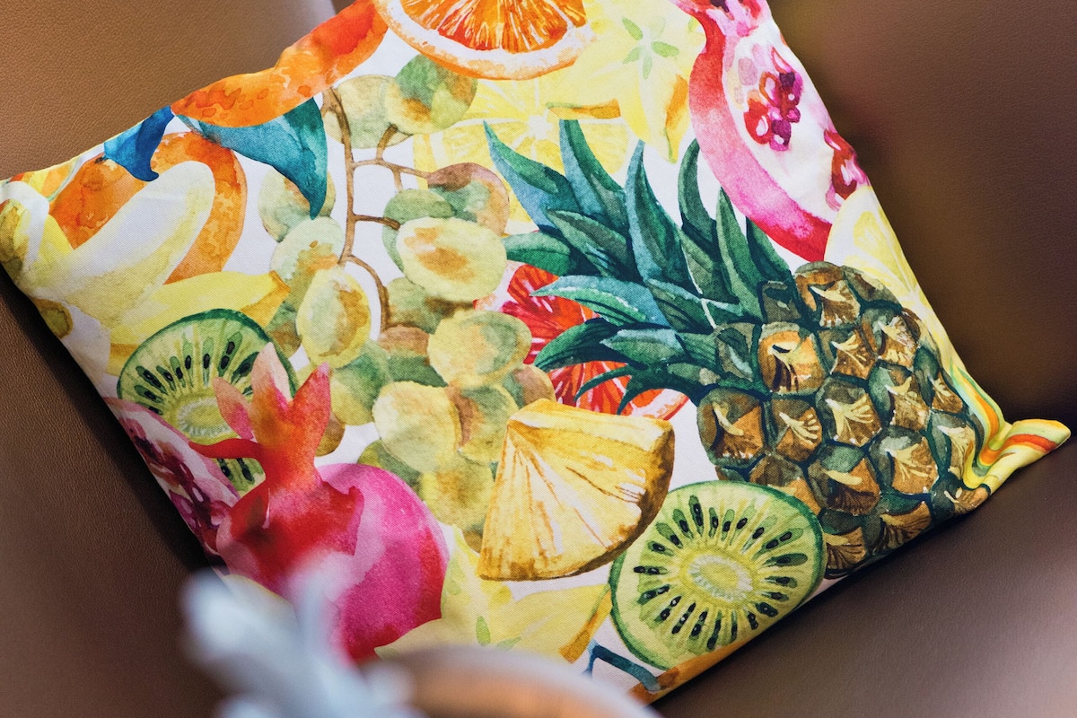 A chair with a colorful cushion featuring fruit patterns.