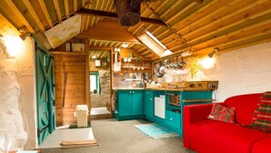 Ein gemütliches Blockhaus-Interieur mit Küche, einem roten Sofa und einer Steinwand.