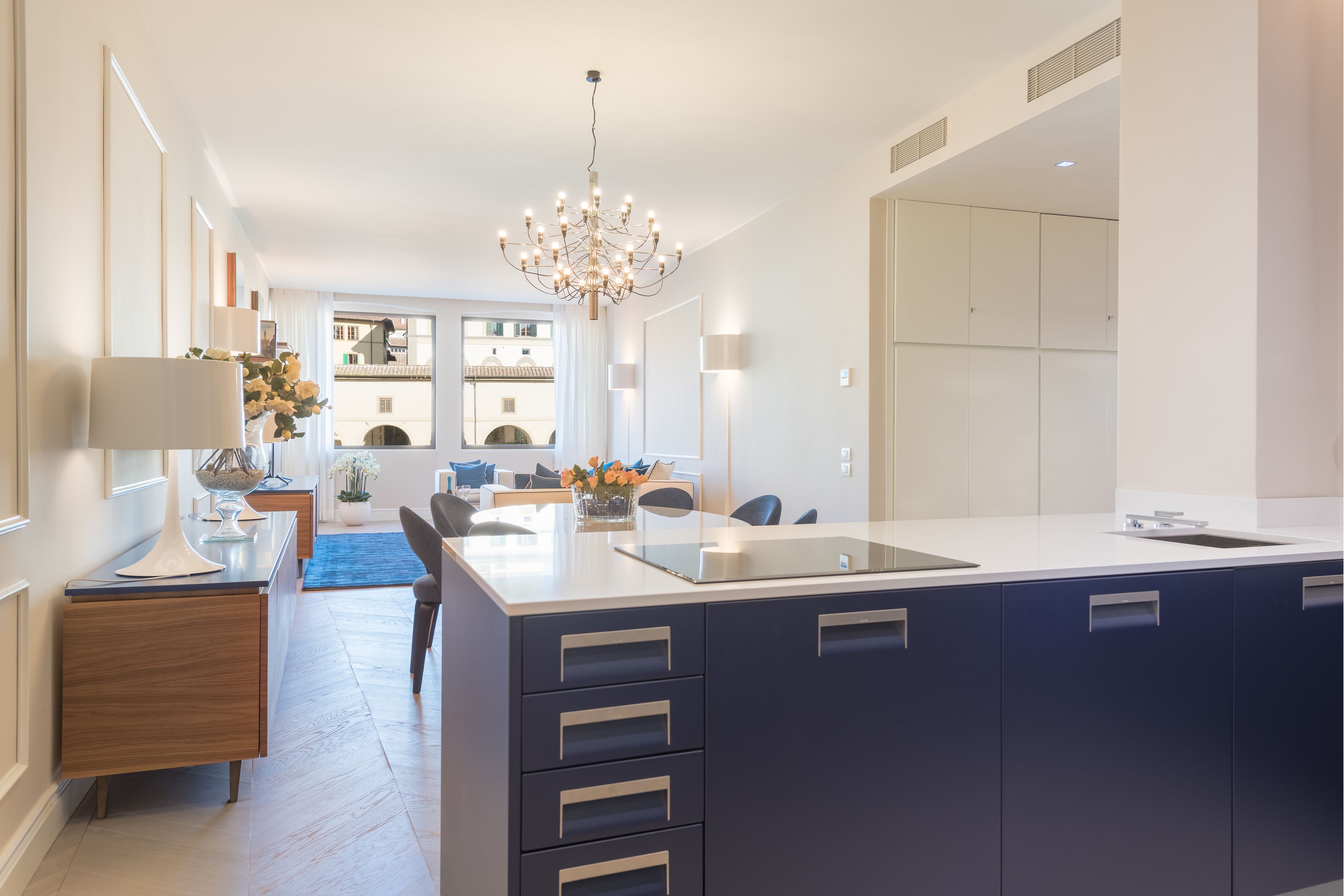 A modern kitchen with a central island, built-in cabinets, and a chandelier.