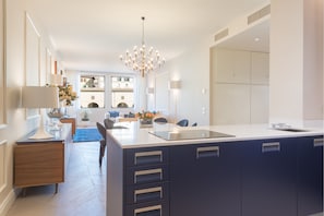 A modern kitchen with a central island, built-in cabinets, and a chandelier.