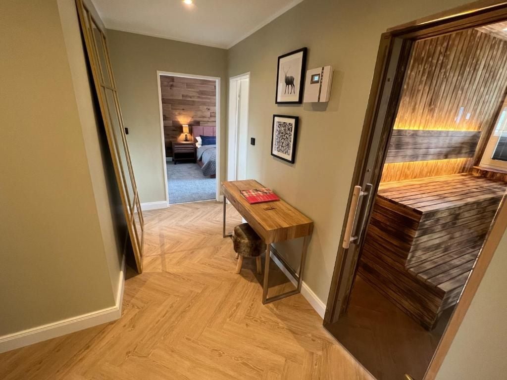 A hallway with a wooden bench, a door with a wooden panel, and a wall with framed pictures.