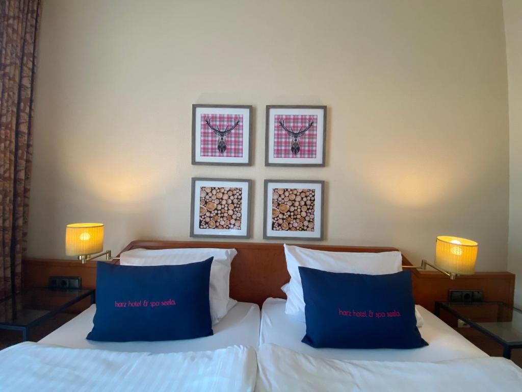 Une chambre d’hôtel avec un lit, deux lampes de chevet et quatre tableaux encadrés accrochés au mur.